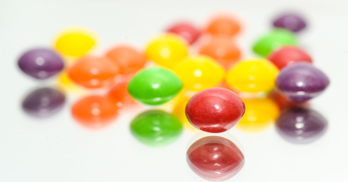 Colorful Skittles candies scattered on a glossy surface