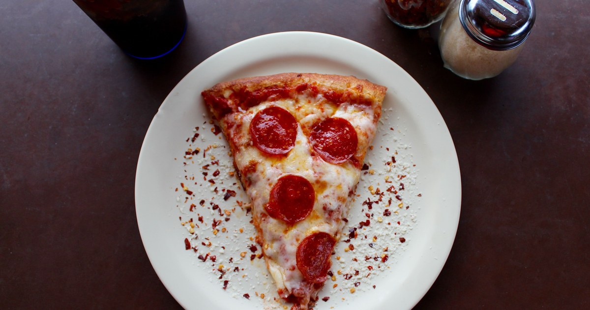 A slice of pepperoni pizza with melted cheese on a white plate