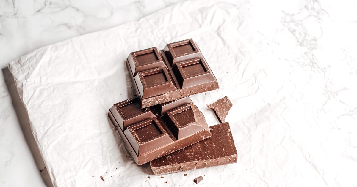 A broken bar of dark chocolate on crumpled white paper