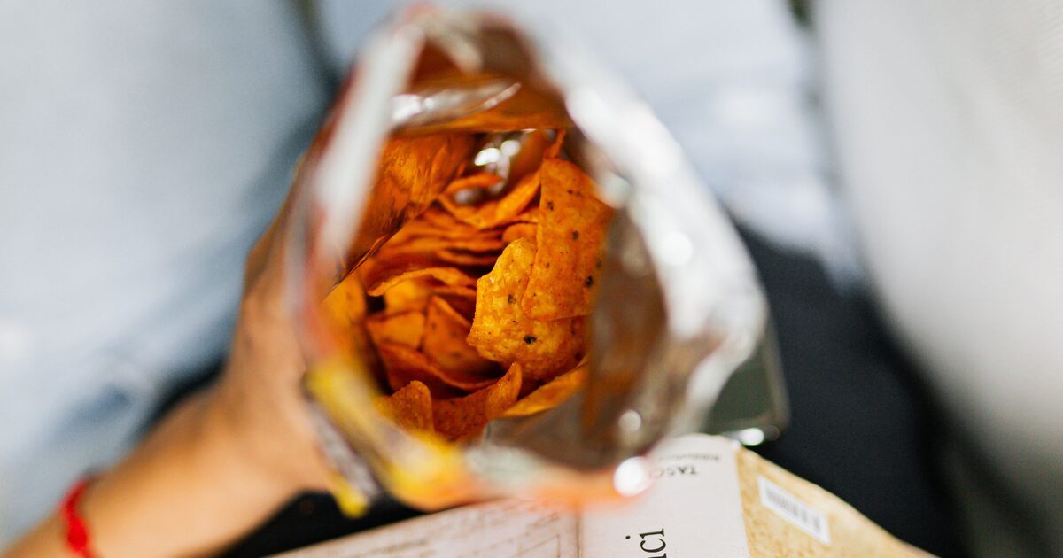 An open bag of flavoured snack chips held over a book